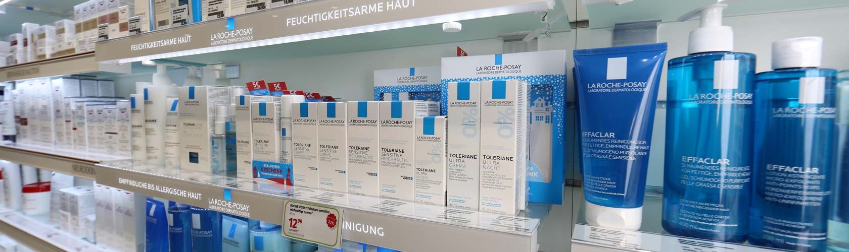 Regale mit Kosmetikprodukten für empfindliche und feuchtigkeitsarme Haut in einer Apotheke.