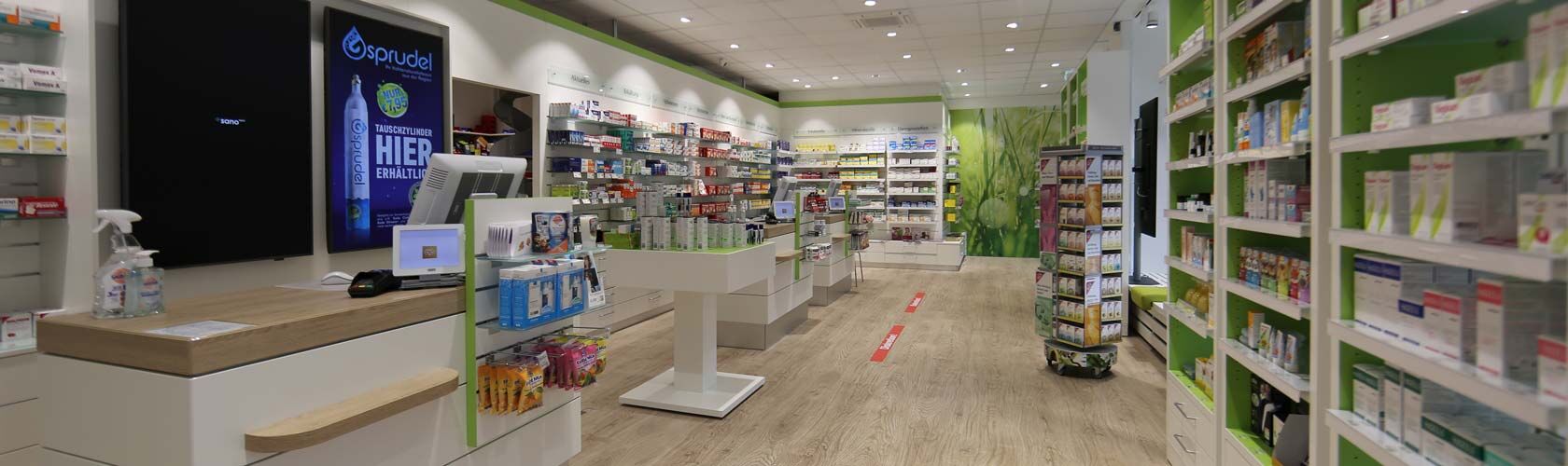 Ein moderner Innenraum einer Apotheke mit Regalen voller Medikamente und einem zentralen Verkaufstresen.